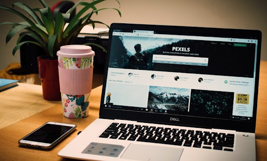 A laptop, a milkshake cup, a smartphone and a green potted plant on an affiliate marketing work table.