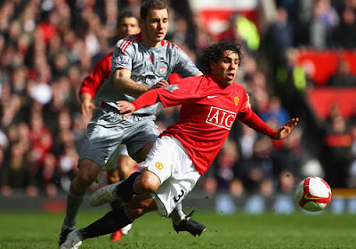 Fabio Aurelio of Liverpool challenges Carlos Tevez of Manchester United