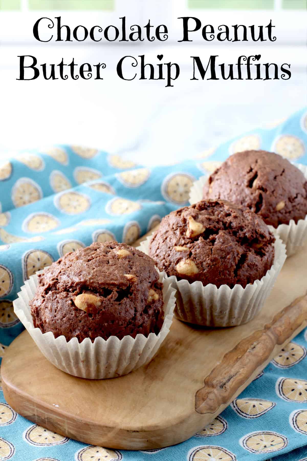 Three Chocolate Peanut Butter Chip Muffins on a wooden board.