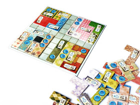 na zdjęciu plansza do gry patchwork a na niej ułożone cztery kwadraty z elementów, obok leży reszta elementów