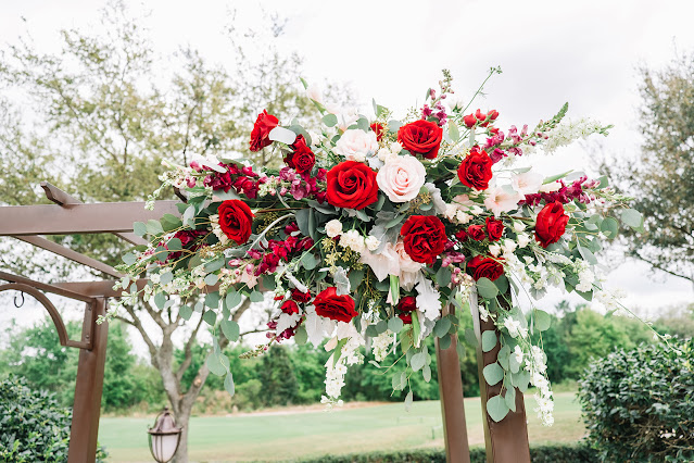 red and pink wedding flowers on ceremony arch