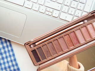 Close up shot of Urban Decay Naked 3 palette against laptop and dress.