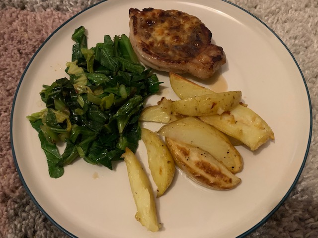 Pork steak topped with cheese, wedges and greens