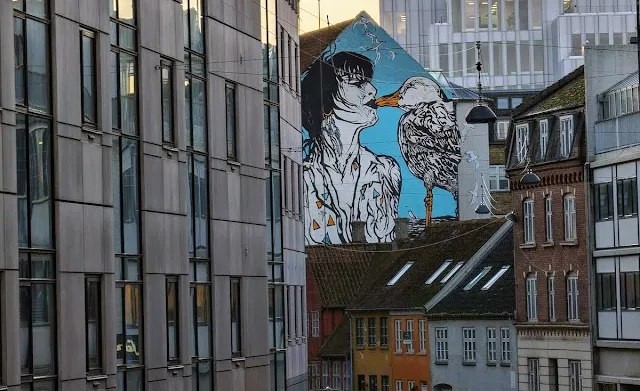 Street art of a person kissing a seagull in Aarhus in January