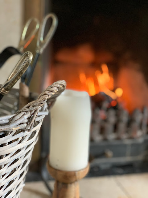 Log basket, church candle and log fire