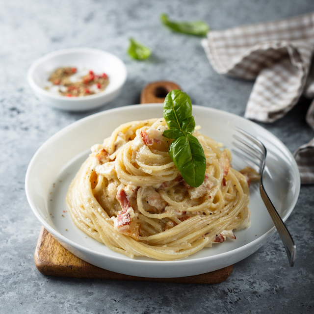 Pyszny makaron Carbonara z posypanym parmezanem i świeżo zmielonym pieprzem.