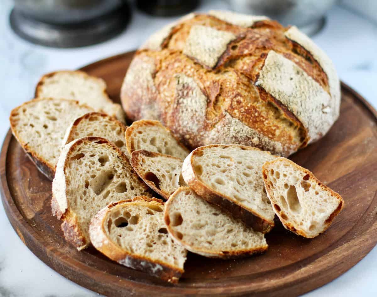 Double Levain Pilsner Bread slices and loaf on a board.