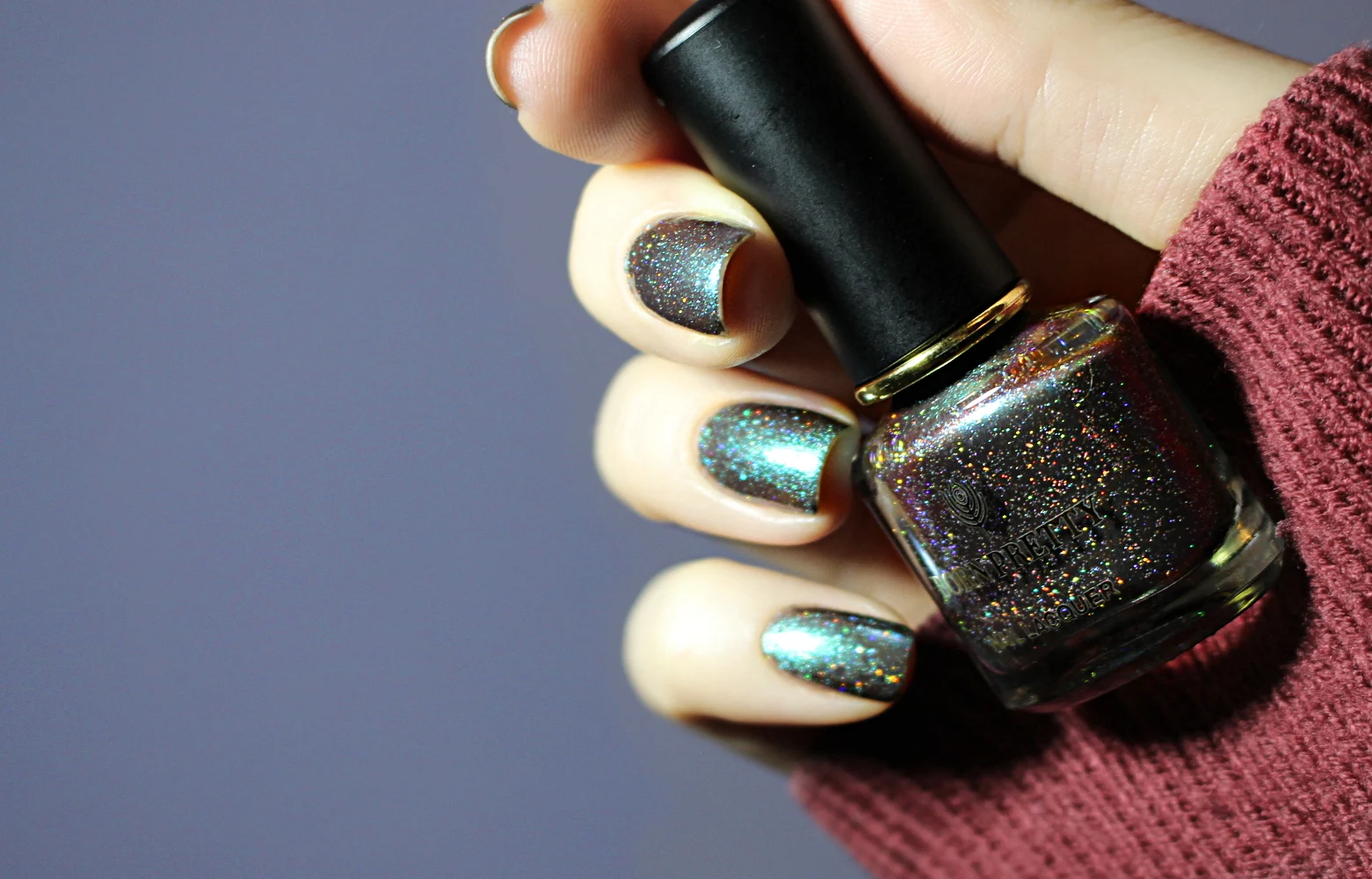 a close-up of a green holographic nail look on short natural nails