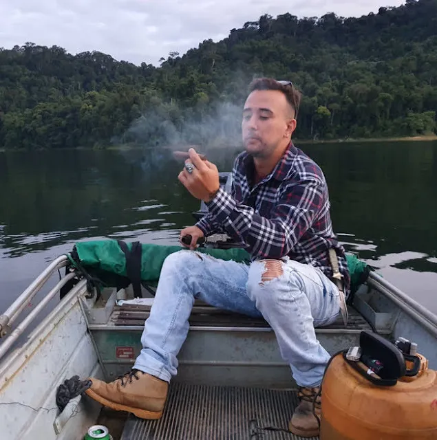 1/2 blue jeans and a flannel with some boots smoking a cigar on the boat