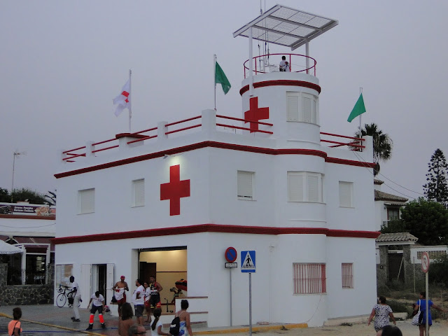 Edificio de vigilancia y socorro de la cruz roja con gente, en la playa de la Barrosa.