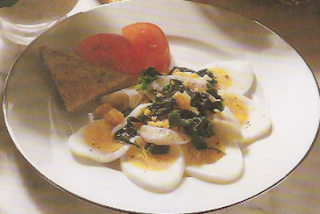 filet rybny na talerzu, obłożony szpinakiem i jajkami na twardo pokrojonymi w plasterki