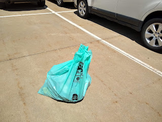 full plastic bag on concrete next to car in parking lot