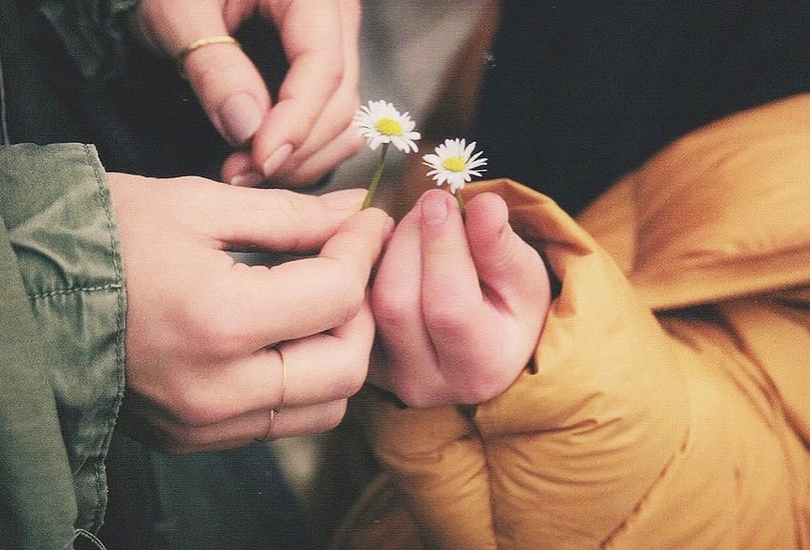 A shot of Hikaru Utada and her son’s hands, holding daisies.