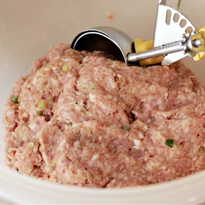 Pork mixture for Asian Pork Meatballs in a bowl with a medium cookie scoop for forming into meatballs