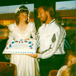 Cindy and Jimmy holding wedding cake during reception surrounded by children