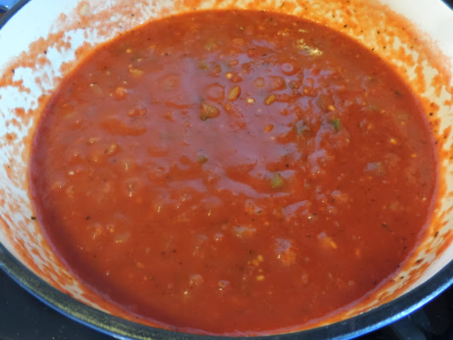 The marinara sauce coming to a simmer in the pan.