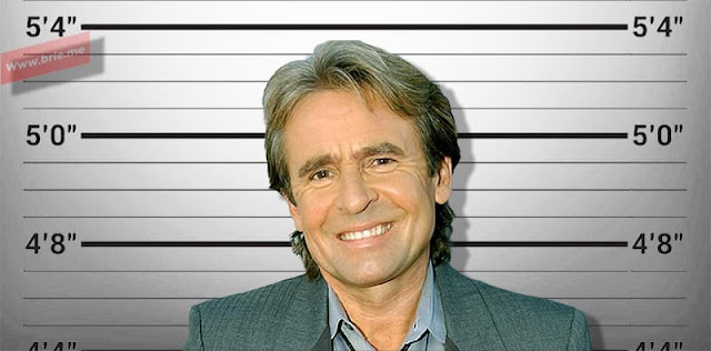 Davy Jones posing in front of a height chart background