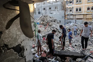 Palestinians assess a residential building destroyed by Israeli air attacks in Gaza