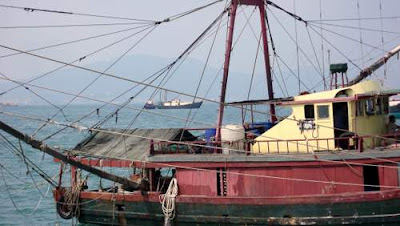 Image of a fishing boat bobbing beside Waglan Island, Hong Kong, 100 meters off of the marine demarcation line for China's nautical boundary.