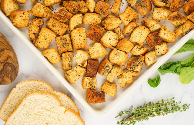 Homemade Butter Croutons on a baking sheet with bread slices on the side.