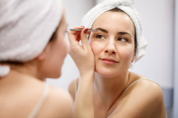 woman tweezing her eyebrows