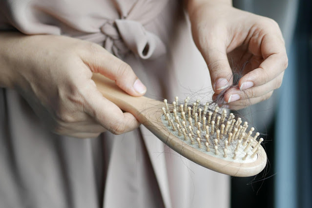 A woman's hand holding strands of fallen hair, highlighting the common problem of excessive daily hair shedding that can be improved through natural remedies.