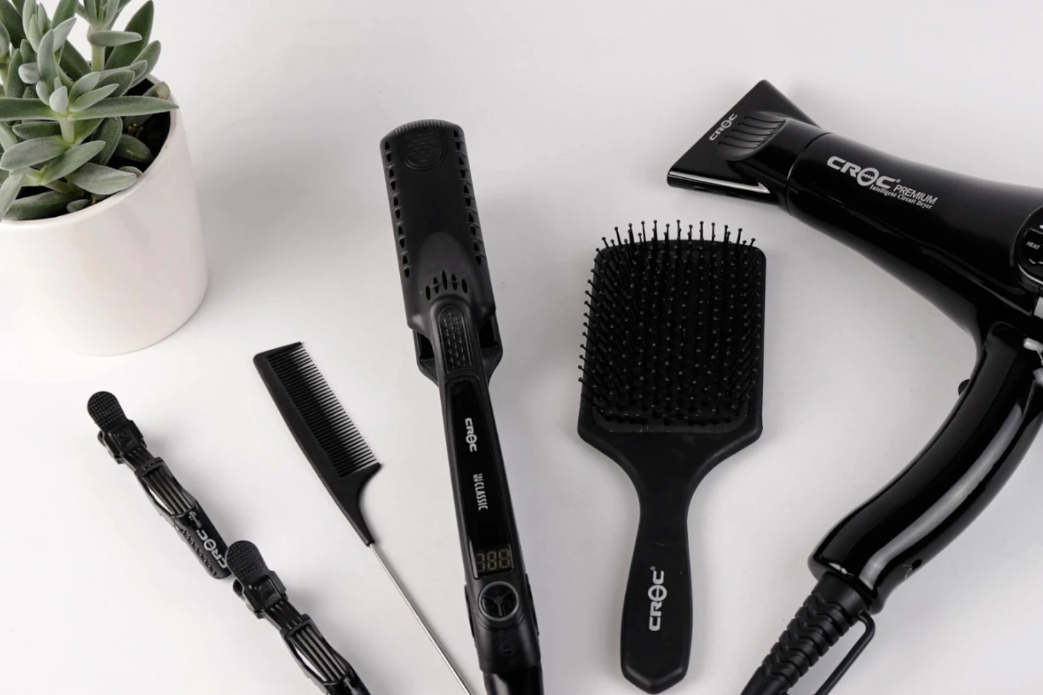 a flatlay of various hair styling tools on a white background