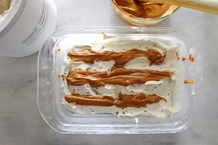 layering churned ice cream with dulce de leche in container
