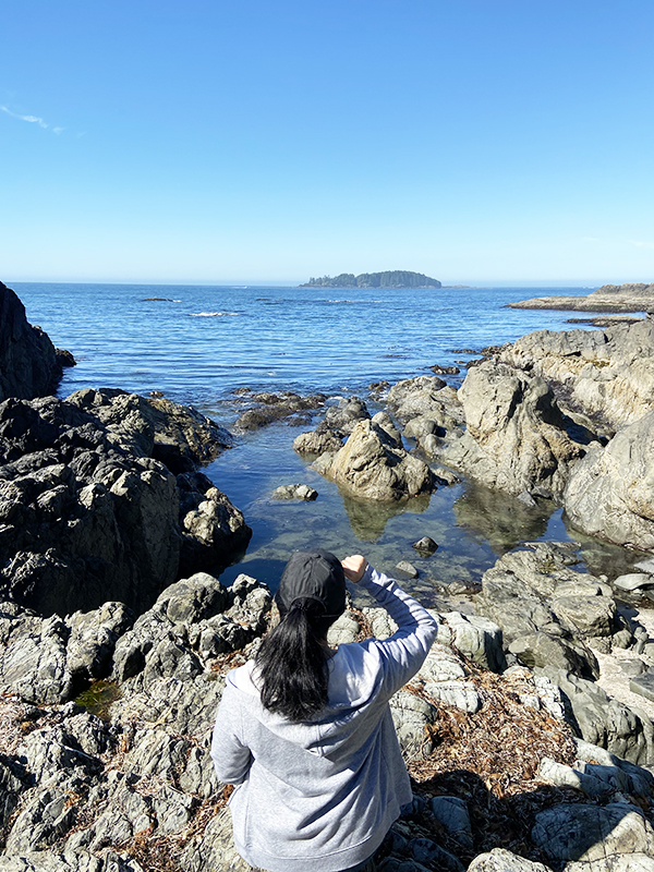 Vancouver beauty, life and style blogger Solo Lisa sits on a rock overlooking the secret cove at Wickaninnish Inn, Tofino.