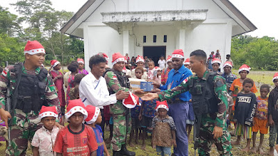  Sambut Nataru, Satgas Yonif Raider 142/KJ Beri Kejutan Bagikan Topi Santa Dan Al Kitab