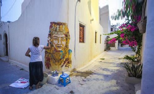 سيدة من سكان جربة تقوم برسم جدارية للملكة الأمازيغية تيهيا