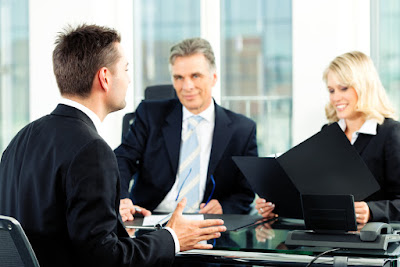 2 sharply dressed businesspeople are meeting with an executive and present a folder with their proposal