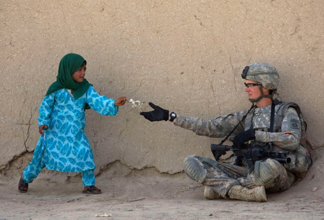 16 Pictures Of Children Restored Our Faith In Humanity - An Afghan girl gives flowers to a US Army soldier during a patrol in the Arghandab Valley in Afghanistan.