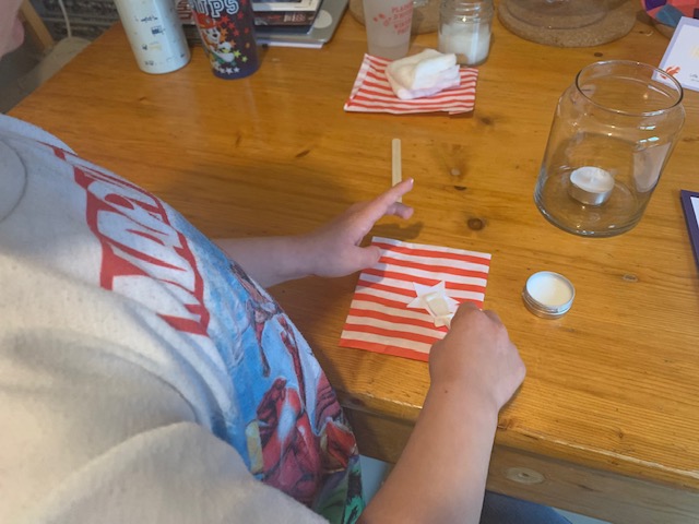 Little boy spreading glue on card stars