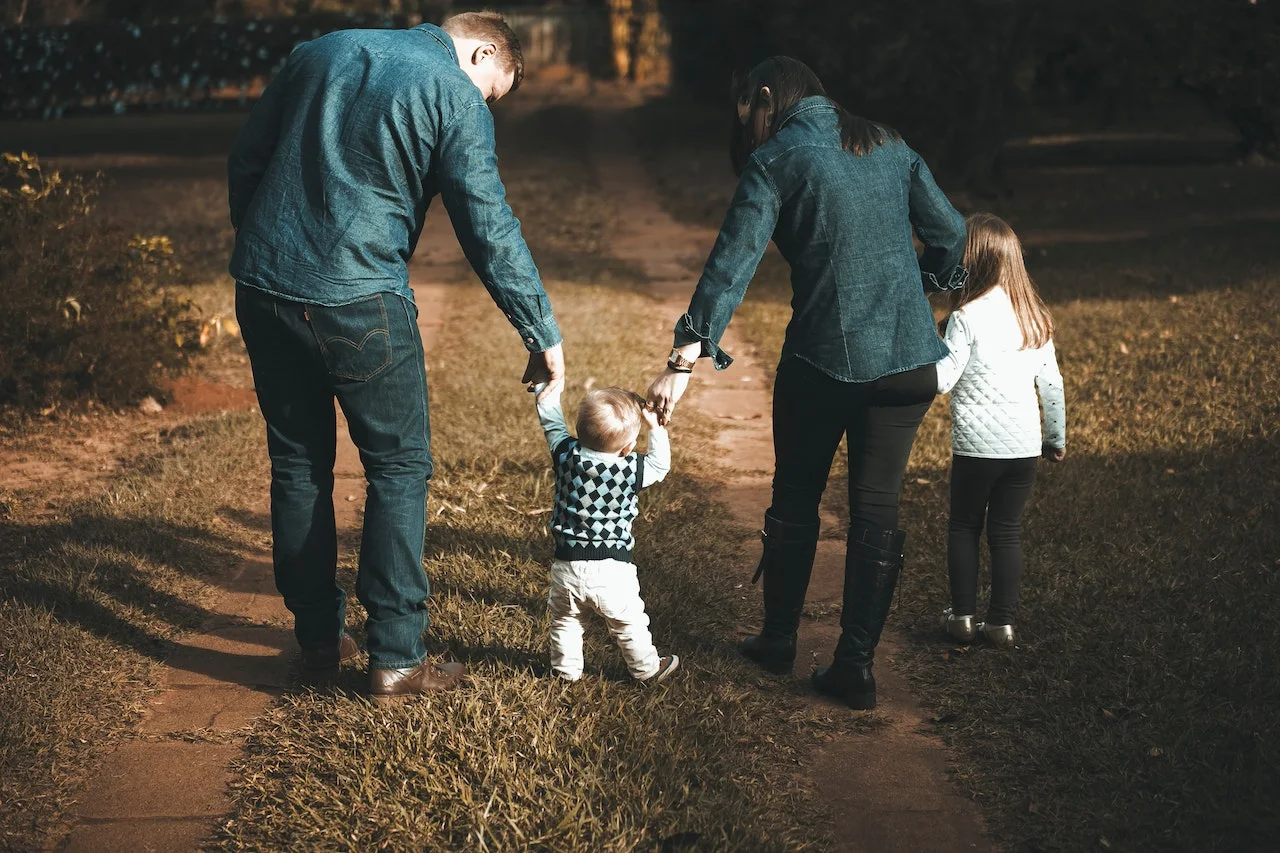 A family walking in the family holding hands and facing away from the camera