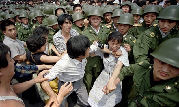 A young woman is caught between civilians and Chinese soldiers near the Great Hall of the People in Beijing