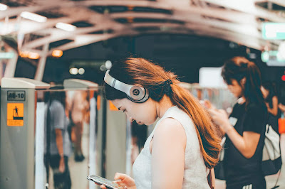 Woman wearing a headphone checking her phone in public