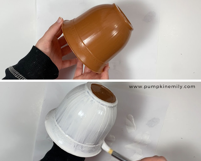 Painting a flower pot with white acrylic paint.