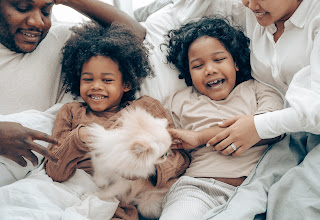 Twin girls lying between their parents and laughing hard