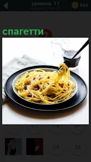 В тарелке находится спагетти и вилкой накручивается, чтобы съесть