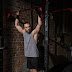 Man in gray tank top holding onto a pull up bar