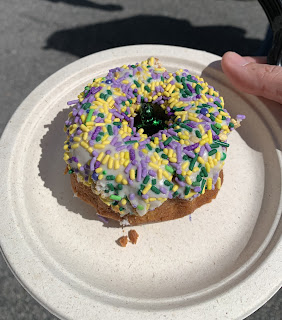 A donut shaped Mardi Gras King Cake with green and purple sprinkles