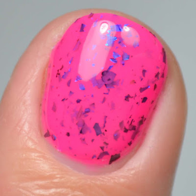 pink nail polish with color shifting flakies single finger close up