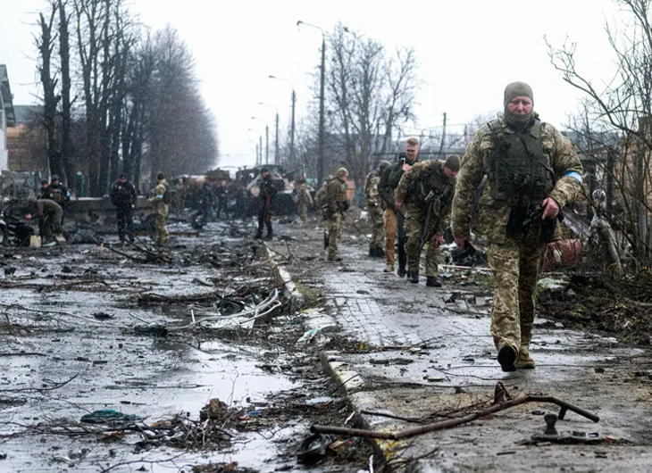 On the road near Bucha, a suburb north of Kyiv, Ukrainian soldiers assess the debris of a wrecked Russian armoured column.