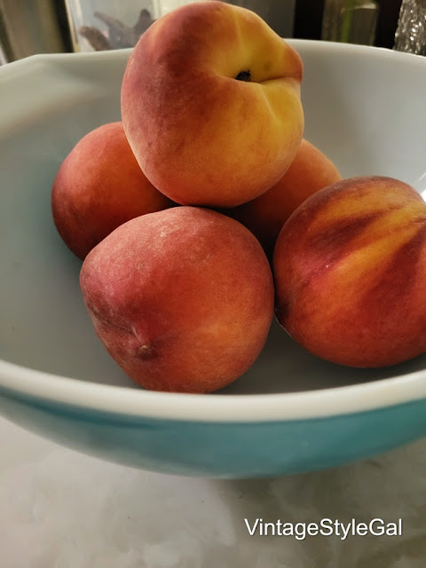 peaches sitting in blue Pyrex bowl on counter