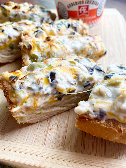 Olive Cheese Bread cut into slices on a wooden cutting board.