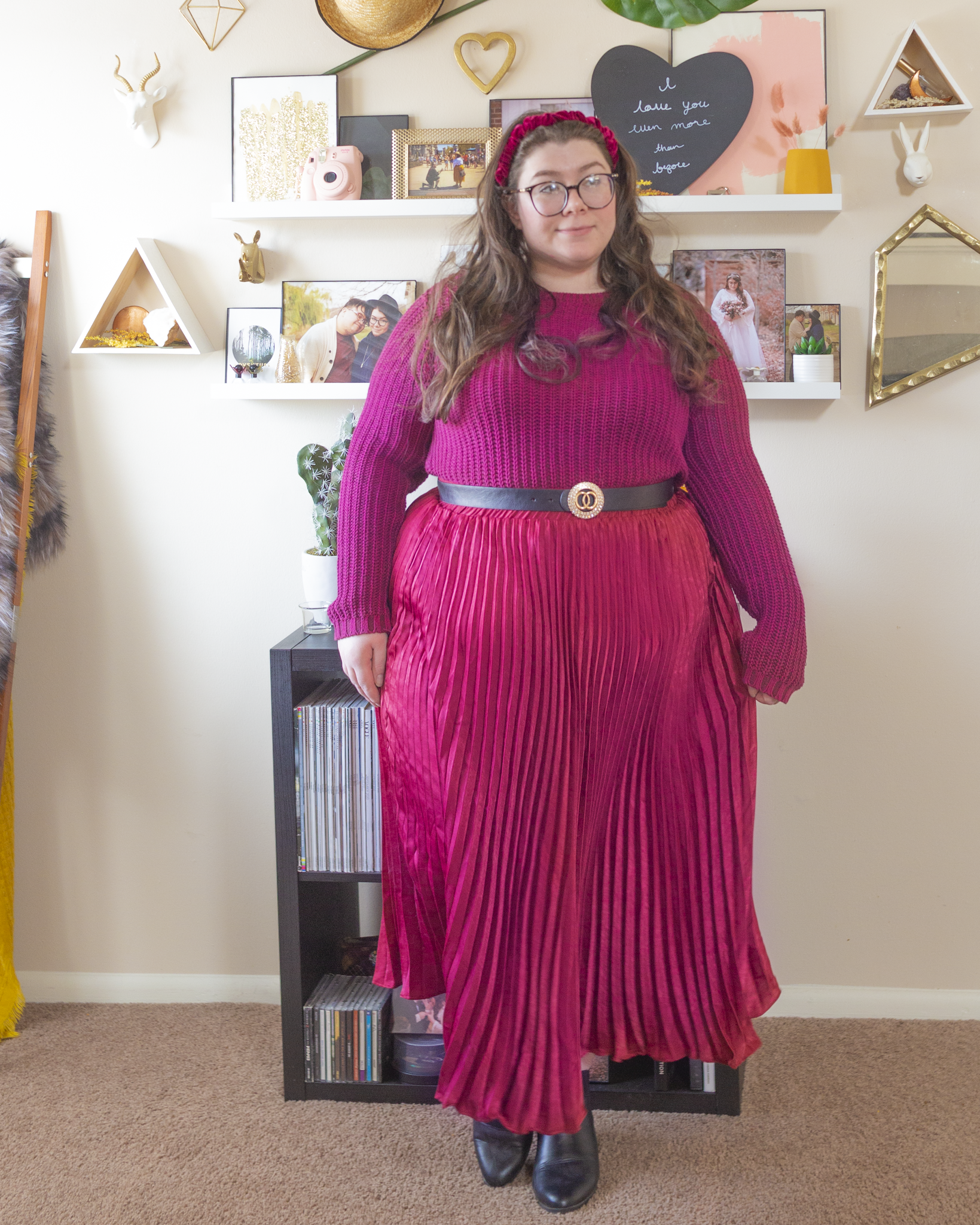 An outfit consisting of a burgundy sweater tucked into a wine pleated maxi skirt, with black Chelsea boot.