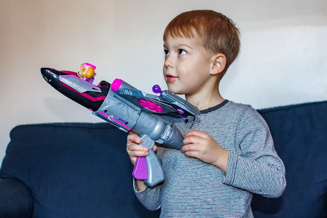 A boy holding Skye's mighty movie jet and looking off camera