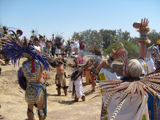 Grupo de danzantes durante el mediodía. Al fondo, visitantes con las manos levantadas recibiendo energía.