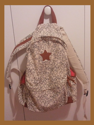 large cream backpack with black star pattern and brown trimming